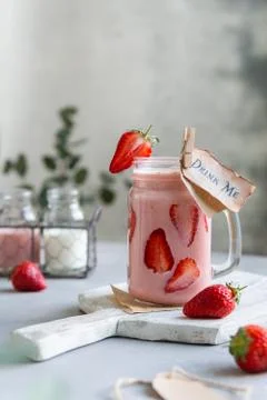 Fresh healthy strawberry smoothie in mason jar with garnish on gray backgroun Stock Photos