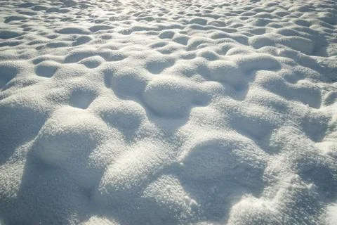 Fresh hilly snow surface background and drifting snowflakes. Bumpy snow covering Stock Photos