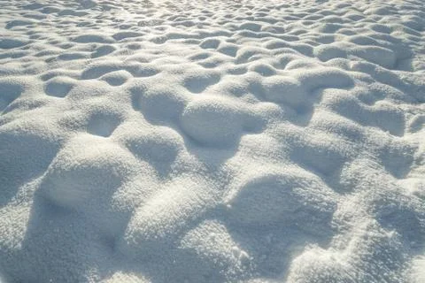 Fresh hilly snow surface background and drifting snowflakes. Bumpy snow covering Stock Photos