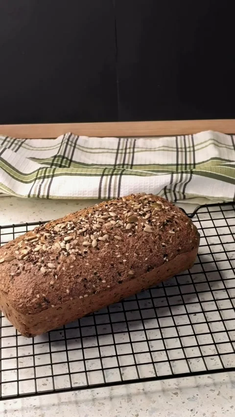 Fresh homemade seed bread cools on a wire rack in the kitchen, healthy baking Video stock 344789467