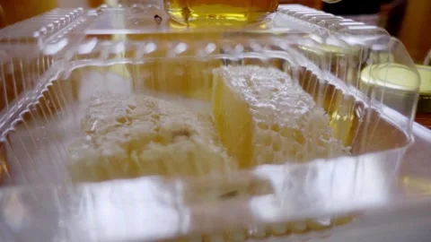 Fresh Honeycomb Pieces in Plastic Container with Natural Honey Texture Stock Footage 334622954
