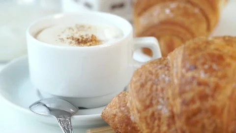 Fresh hot cappuccino coffee on background of baked french croissants. Breakfast Stock Footage 150086532