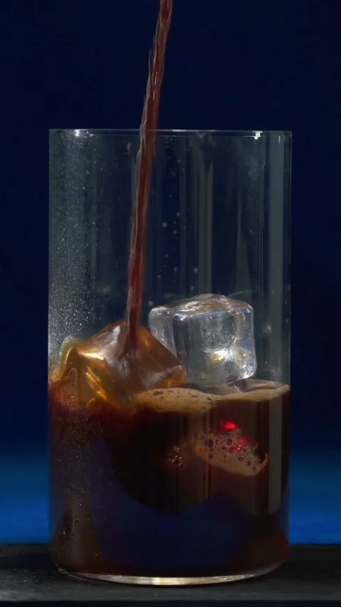Fresh hot coffee being poured into glass with ice cubes for iced drink Stock Footage 335422254