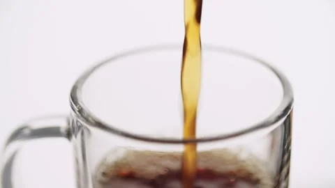 Fresh hot coffee being poured into a transparent glass mug on a white backg.. Video stock 337805252
