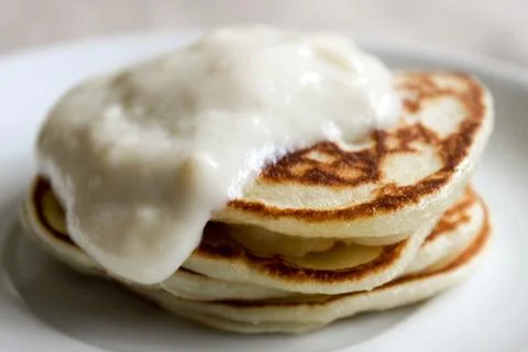Fresh hot flapjack pancakes stack on white plate on natural light linen table Stock Photos