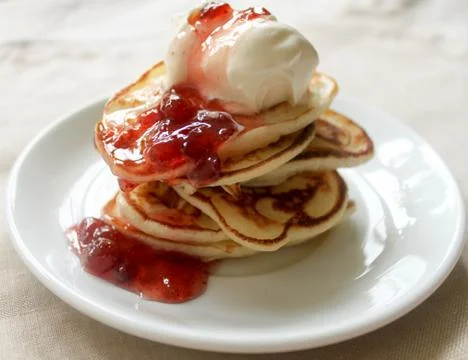 Fresh hot pancakes stack with strawberry jam and sour cream on white plate on Stock Photos