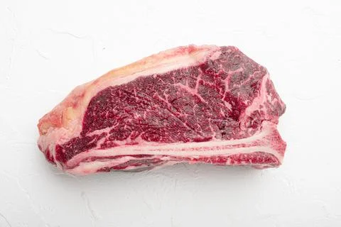 Fresh, huge and appetizing dry aged club steak, on white stone background Stock Photos
