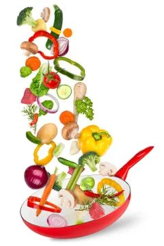 Fresh ingredients falling flying into red frying pan creative cooking concept Stock Photos