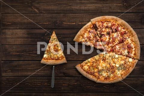 Fresh italian pizza and a pie spatula with one slice on the wooden background Stock Photos