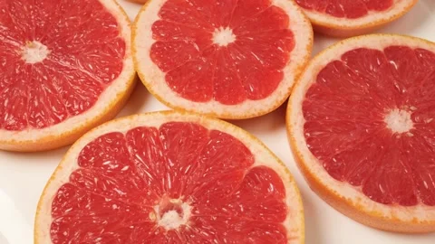 Fresh juicy grapefruit slices rotating on a white background Stock Footage 343435307