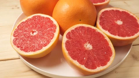 Fresh juicy sliced grapefruit rotating on a plate Stock Footage 341281025