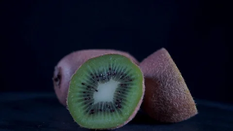 Fresh kiwi fruit sliced in half on black background Stock Footage 129420741