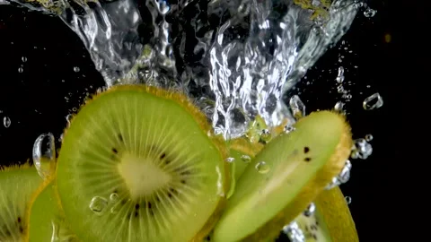 Fresh kiwis slices falling into clear water with big splash on black background. Vídeo Stock 150567086
