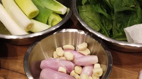 Fresh leeks, spinach, shallots, and garlic in a kitchen prep scene Stock Footage 330138568
