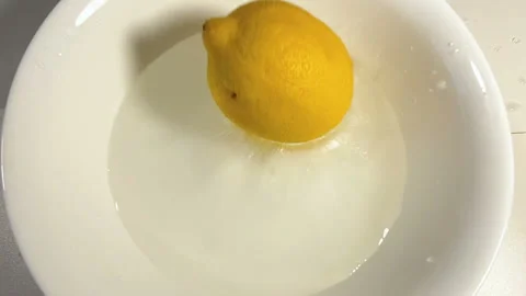 Fresh lemon fall down in plate with water, closeup, super slow motion Stock Footage 132780435