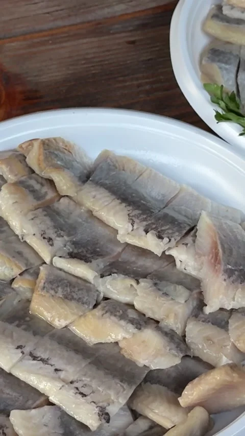 Fresh Lemon Juice Squeezed by Hand Over Sliced Herring for Flavorful Seafood Stock Footage 345728097