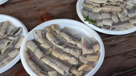 Fresh lemon juice squeezed over sliced herring on white plastic plate during Stock Footage 345728617