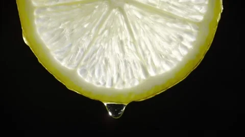 Fresh lemon slice dripping juice on black background macro shot of citrus fruit Stock Footage 340952963