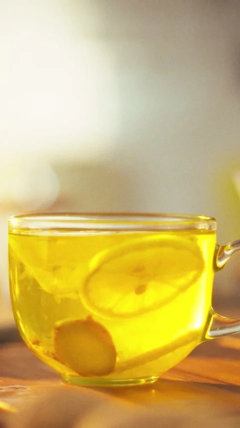 Fresh lemon slices and ginger pieces swirl in a clear glass cup while hot te Stock Footage 342718377