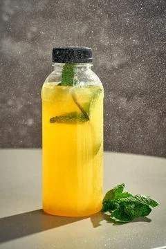 Fresh lemonade in a bottle with a splash of water on it. Gray background. Stock Photos