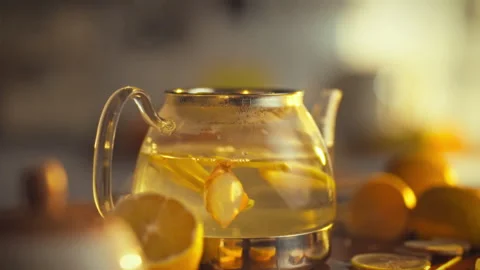 Fresh lemons and ginger infuse in a clear glass teapot surrounded by kitchen Video stock 331473342