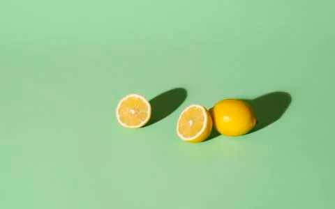 Fresh lemons cut in half on a green background. Summer fruits Stock Photos