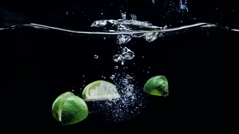 Fresh lemons fall into the water on a black background Stock Footage