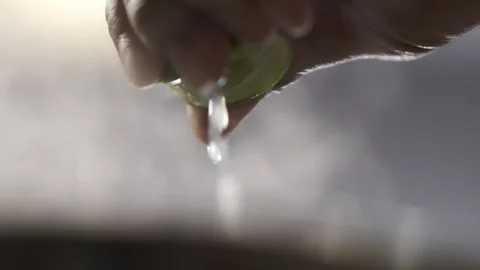 A fresh lime is being squeezed with a lot of juice comes out with smoke in the s Stock Footage 145354706
