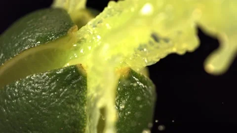Fresh Lime fruit squirting with juice in slow motion in black background 4K Stock Footage 199130786
