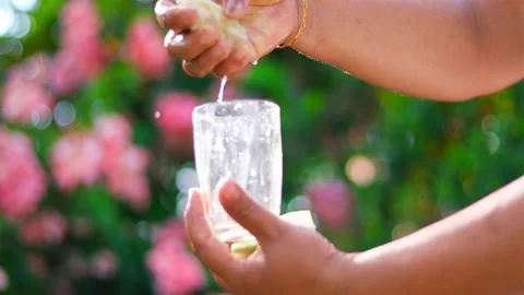 Fresh lime juice being squeezed into a glass in bright natural sunlight Vídeos de archivo 339760704