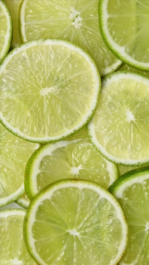 Fresh lime slices rotate in a vertical frame, forming a citrus pattern with Stock Footage 346672364