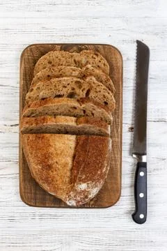 A fresh loaf of bread and a bread knife on a rustic old white table. slice of Stock Photos