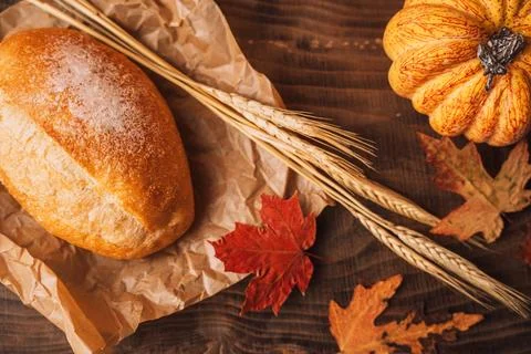 Fresh loaf of bread with ears of wheat and pumpkin on a wooden table Stock Photos