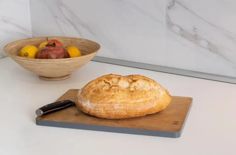 Fresh loaf of bread on kitchen cutting board. Stock Photos