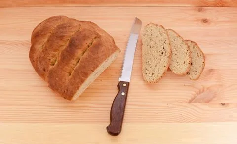 Fresh loaf of bread with a knife and three slices Stock Photos