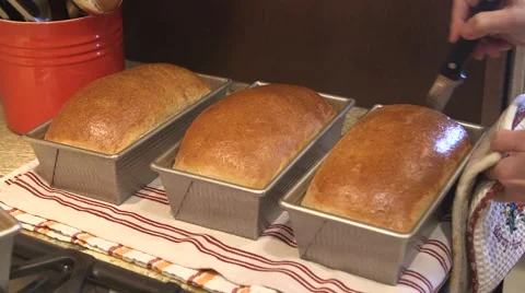 Fresh loaves of bread being removed from bread pan Stock Footage 45618443