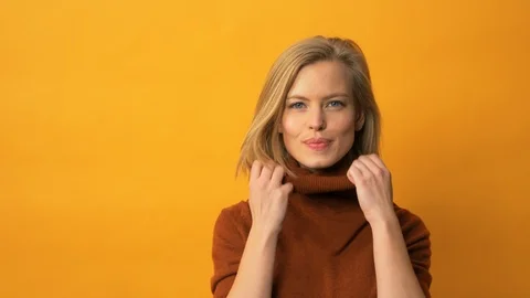 Fresh looking model wearing turtleneck sweater in front of yellow background Stock Footage 103628748
