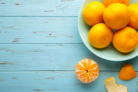 Fresh mandarin oranges fruit on mint bowl on blue wooden background. Stock Photos