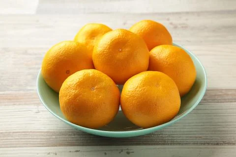 Fresh mandarin oranges fruit on mint bowl on grey wooden background. Stock Photos