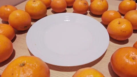 Fresh Mandarins Encircling Empty White Plate in Minimalist Table Composition Stock Footage 337930817