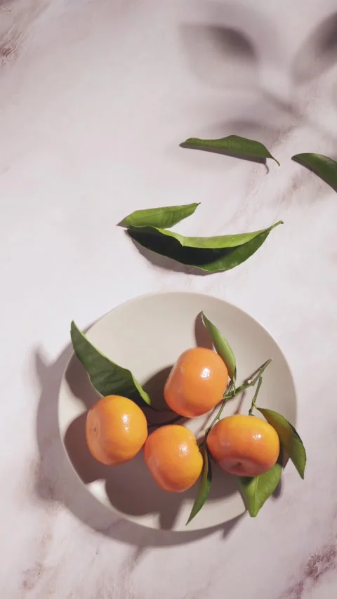 Fresh mandarins on plate with moving leaf shadows Stock Footage 332643276
