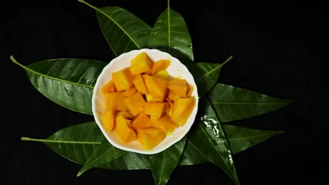 Fresh mango cubes served in white bowl on green mango leaves background Stock Footage 337140554