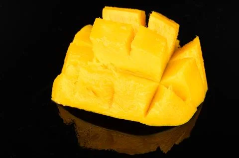 Fresh mango cut into cubes on black surface ready to eat Stock Photos