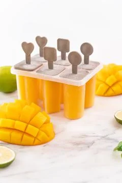 Fresh mango fruit popsicle ice in the plastic shaping box on bright marble .. Stock Photos