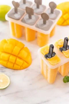 Fresh mango fruit popsicle ice in the plastic shaping box on bright marble .. Stock Photos