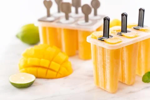 Fresh mango fruit popsicle ice in the plastic shaping box on bright marble .. Stock Photos