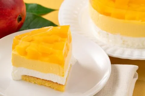 Fresh mango mousse cake served on a white plate. Stock Photos
