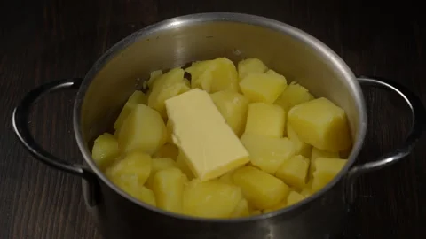 Fresh mashed potatoes mashed with a metal masher in a saucepan on a table Stock Footage 306090827
