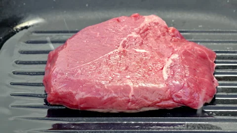 Fresh meat awaiting cooking process, uncooked beef slice with marbling on grill Stock Footage 325840137