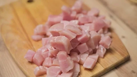 Fresh meat cut into small cubes on a wooden cutting board in a kitchen. This 库存影片 338298359